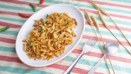 Delicious fried flat rice noodle or char kway teow or kwetiau with egg and vegetables. Indonesian...