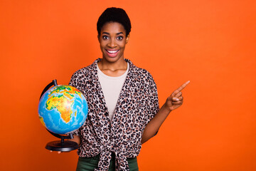 Portrait of attractive cheerful trendy girl holding globe showing copy space ad isolated over...