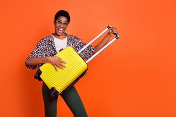 Portrait of amazed excited person hold suitcase prepare weekend flight isolated on orange color background