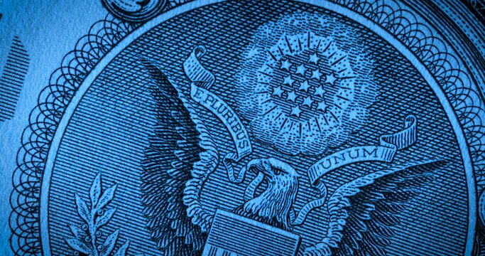 Macro shot of the back side of a one dollar bill with stars and an eagle in blue soft light. US paper banknote. American money. Banking, finance, business.