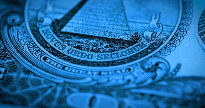 One dollar paper banknote in blue soft light. Macro shot of part of 1 dollar bill with symbol pyramid and motto novus ordo seclorum. U.S. currency with the fifth president George Washington.