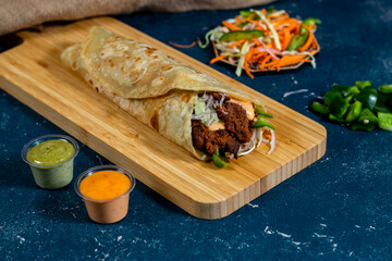 Beef Seekh Kebab shawarma Wrap with salad dip and sauce isolated wooden board side view of fastfood