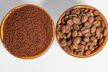 Cups with roasted coffee beans and ground coffee, white background and copy space.