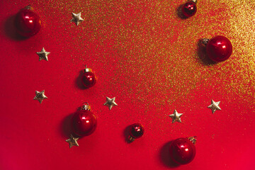Christmas and New Year card with golden glitters, confetti stars and red Christmas balls on red...