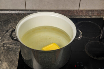 Cooking of marijuana butter in hot water on electric cooker in kitchen