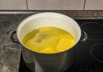 Cooking of marijuana butter in hot water on electric cooker in kitchen