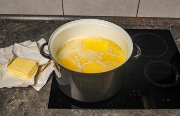 Cooking of marijuana butter in hot water on electric cooker in kitchen