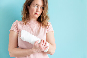Woman with broken arm, fractured wrist. Hand in a plaster bandage, gypsum bandage. - obrazy, fototapety, plakaty
