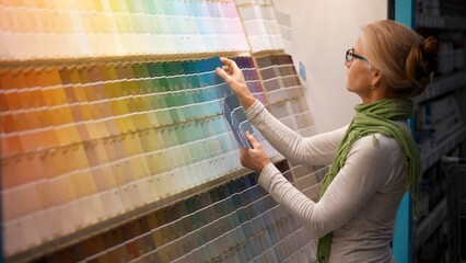 Mature woman looking at paint chips in a big box hardware store. Concept of shopping experience for home improvement.