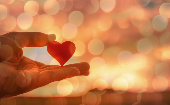 Hand holding heart and Christmas lights bokeh background 