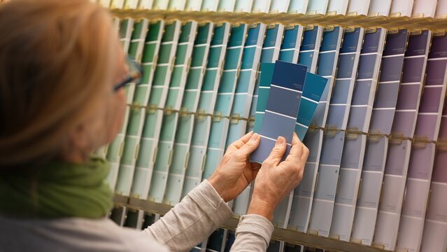 Mature woman looking at paint chips in a big box hardware store. Concept of shopping experience for home improvement.