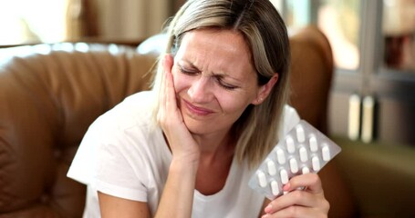Portrait of woman hurting tooth and taking painkillers pill