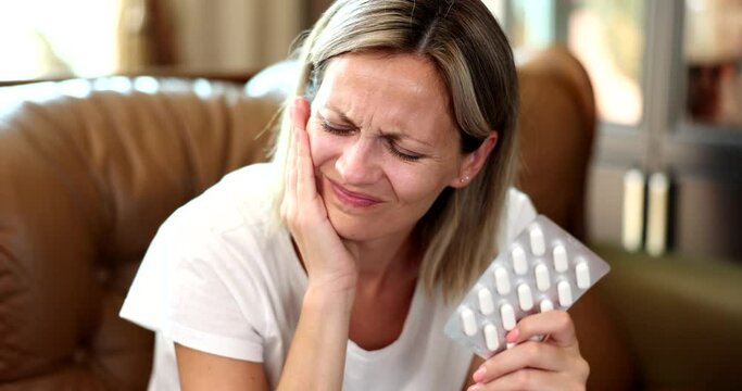 Portrait of woman hurting tooth and taking painkillers pill