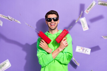 Portrait of good mood cheerful guy brunet hairdo wear green hoodie hold guns shooting money...