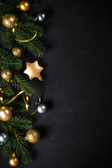 Black christmas background with fir tree and trendy golden decorations. Flat lay image with copy space.