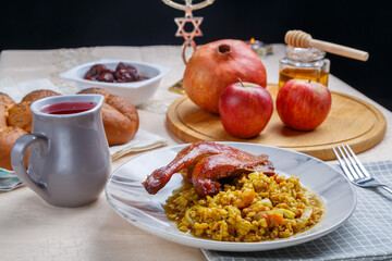 Rosh Hashanah next to pomegranate honey apples wine and challah on a white table and candles next...