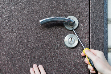 Handyman installing door lock in front door. Checking the door lock with crewdriver for operability.