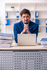 Young male employee unhappy with excessive work in the office