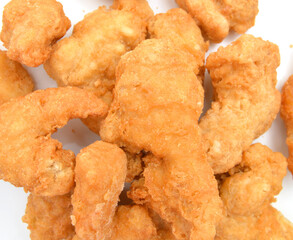 Heap of frozen bread crumbed chicken strips on white.