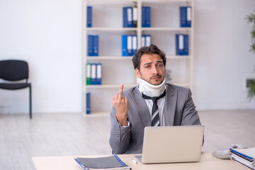 Young male employee after car accident working in the office