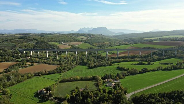 Panoramic view from a drone on passenger train crossing the railway flyover. Overlooking the surrounding mountains in southern France