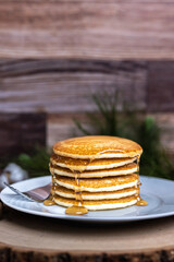 A large plate of pancakes with a fork and syrup poured on