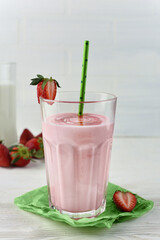 A glass of strawberry milk smoothie. Healthy strawberry smoothie in a glass with berries over. Protein cocktail with strawberry syrup, berries and green paper cocktail straws.