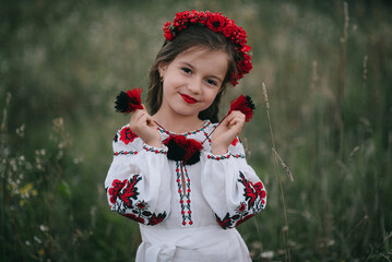A young girl with very long hair in Ukrainian national dress embroidery and hoop with poppies on...