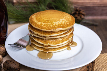 A large plate of pancakes with a fork and syrup poured on