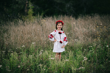 A young girl with very long hair in Ukrainian national dress embroidery and hoop with poppies on...