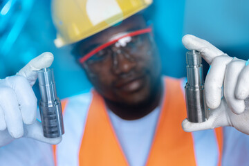 Engineer african man worker checks and inspects metal part after processed on CNC automated...