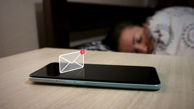 Text message notification appears on the mobile smartphone that is lying on the bedside table. Animated icon like hologram above phone. Mobile phone against the background of  sleeping woman in bed