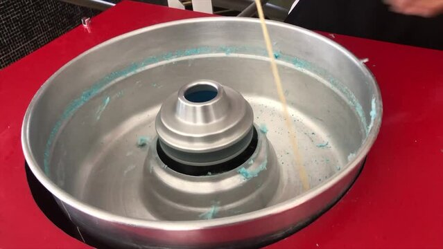 Making blue cotton candy in traditional machine in detail.