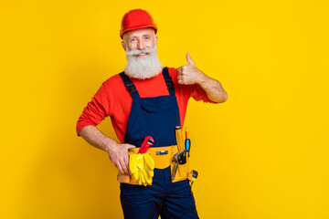 Photo portrait of handsome granddad confident mechanic showing thumb up cheery dressed safety uniform isolated on yellow color background