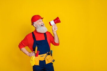 Photo of impressed cool old guy dressed uniform overall red hardhat making announcement empty space...
