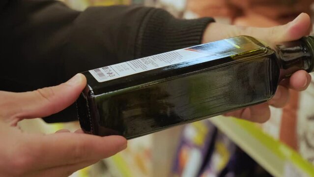 Close up of two male hands holding bottled product in store to read ingredients contents. Shopping concept. Conscious choice. 4k video