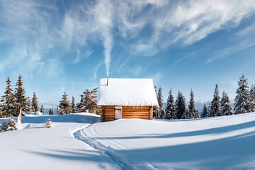 Fantastic winter landscape with wooden house and smoke from chimney in snowy mountains. Christmas holiday concept. Carpathians mountain, Ukraine, Europe