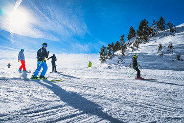 Group of people skiing and snowboarding down the ski slope or piste in Pyrenees Mountains. Winter ski holidays in El Tarter, Grandvalira, Andorra - obrazy, fototapety, plakaty