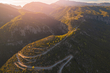Aerial top view winding road in middle forest Tazi Canyon Antalya, Turkey sunset light