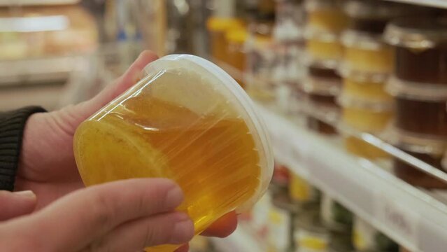 Male hands holding package of honey in store to read ingredients contents and pull date. Shopping concept. Conscious choice. 4k video