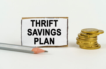 On a white background, a pencil, coins and a sign with the inscription - Thrift savings plan