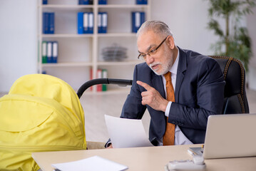 Old male employee looking after new born at workplace