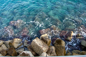 El tranquilo mar azul de la ciudad mediterránea de Alicante tan cristalina que se ven las piedras del fondo con las textura de las olas.