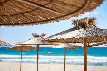 Beach wooden umbrellas on sand by sea