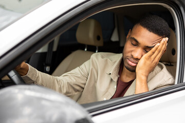 Stressed man sitting in the driver's seat of a car looks into the windshield 