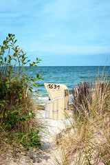 Looking through a path on the dike to the beach chair 1631 by the Baltic Sea.