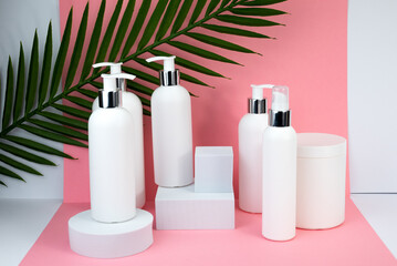 A white cosmetic bottles mockup. White plastic bottles with shampoo and conditioner and shower gel on a pink background. Mockup cosmetic bottle with place to add text on pink background