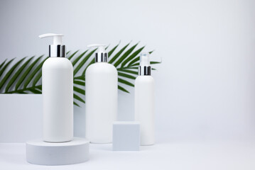 Set of white cosmetic bottles mockup with palm leaf. White plastic bottles with shampoo and...