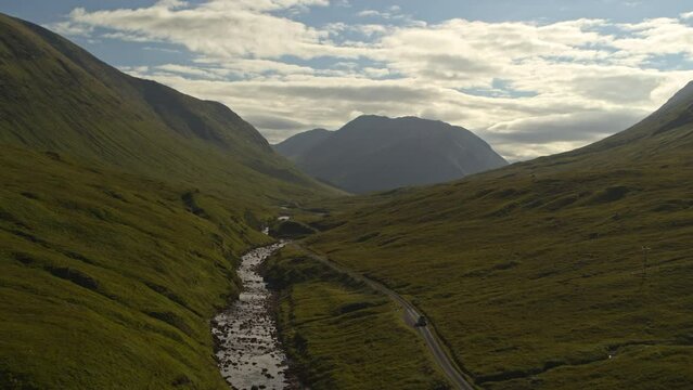 Aerial flyover view of mountains and Road to Skyfall / Glencoe, Scotland