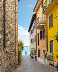 Een smal steegje met winkels en cafés die leidt naar de promenade aan het meer in de stad Sirmione, Italië, aan de oevers van het Gardameer.